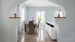 A modern dining area with a table and chairs, a white sofa, and a ceiling with an arch. - Old Port Spetses Mansion (Spetses)