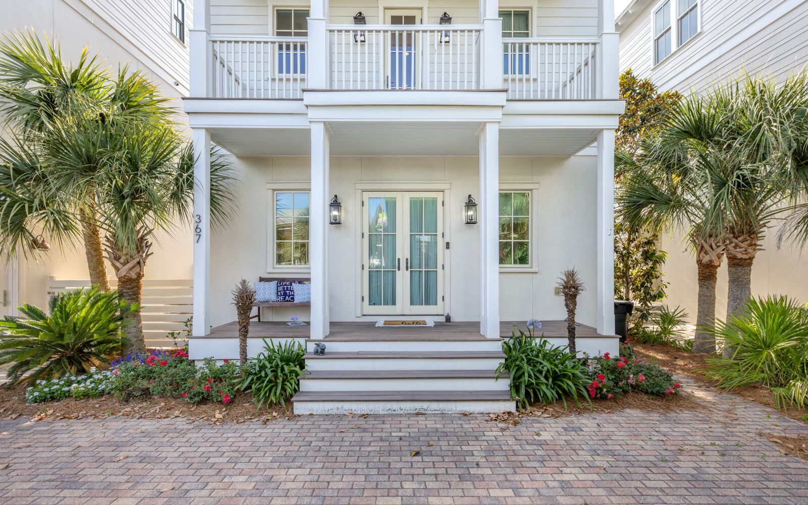 A two-story building with a front porch, a central door, and a small bench.