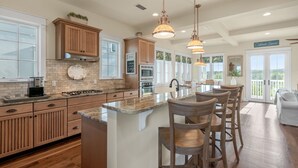 A spacious kitchen with wooden cabinets, a large island with bar stools, and pendant lighting. - Gulf Views-Resort Style Community! (Santa Rosa Beach)