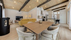 A modern living space with a wooden dining table, a yellow sofa, and a kitchen area.