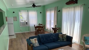 A living room with a blue sofa, wooden coffee table, and a dining area with a table and chairs. - The Boat House - Water Front, Wifi, Pet Friendly 1 Bedroom Home by RedAwning (Norfolk)