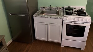 A compact kitchen with a stainless steel refrigerator, a white stove with an oven, and a granite countertop sink. - Boat House Studio - Water Front Pets Wifi Smart Tv Apts by RedAwning (Norfolk)