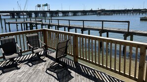 A wooden deck with outdoor seating and a view of a pier extending into a body of water. - Boat House Studio - Water Front Pets Wifi Smart Tv Apts by RedAwning (Norfolk)