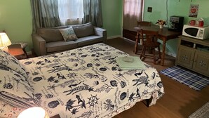 A cozy room with a bed, a sofa, a dining table, and a television. - Boat House Studio - Water Front Pets Wifi Smart Tv Apts by RedAwning (Norfolk)