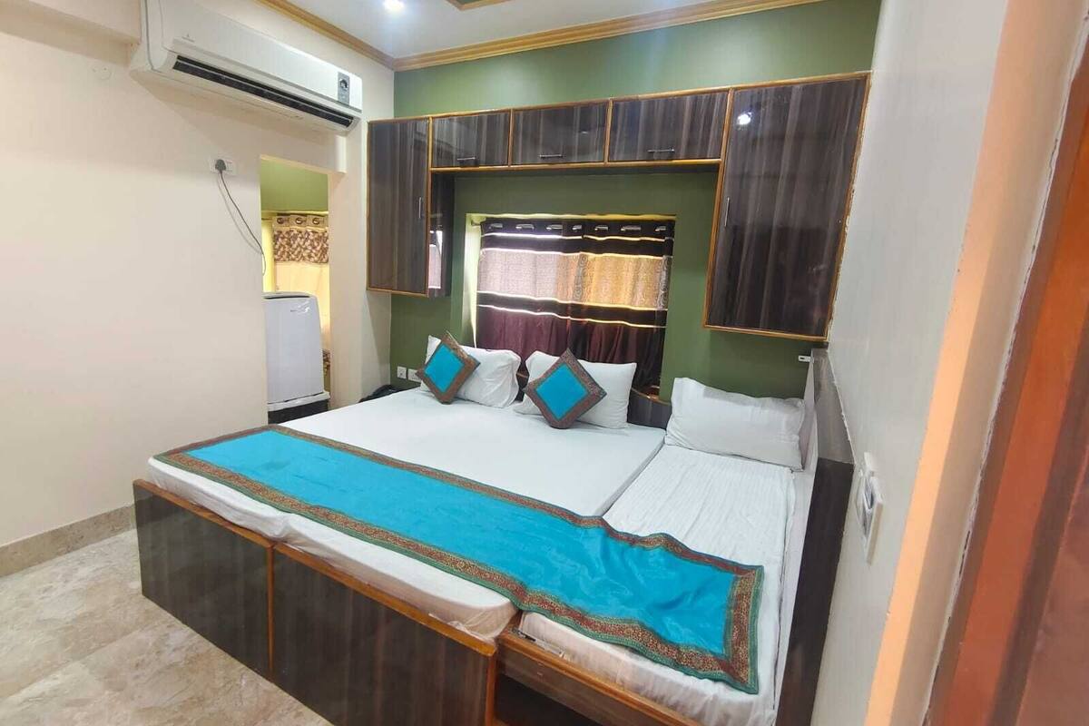 A bedroom with a bed, a wardrobe, an air conditioning unit, and a curtain.