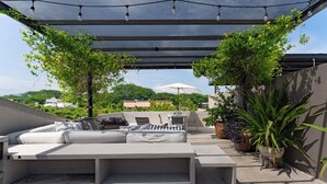 An outdoor patio with a sofa, chairs, and a table under a shaded area with string lights. - Private Rooftop Terrace + Walkable to the Beach (Bays of Huatulco)