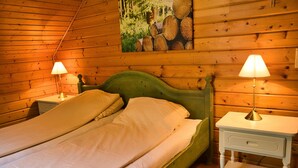 Una stanza con due letti singoli, pareti in legno, un quadro raffigurante tronchi e due comodini con lampade.