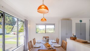 Un comedor con una mesa de madera dispuesta para seis personas, ventanas amplias y vistas al exterior.