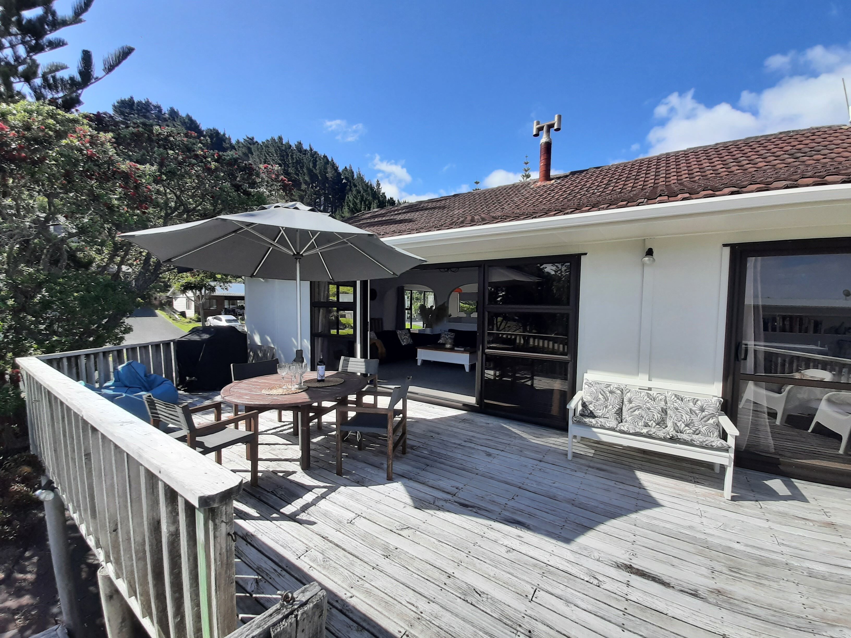 A wooden deck with outdoor furniture, a covered seating area, and a view of a forested hillside.