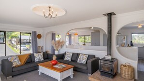 Una sala de estar moderna con un conjunto de sofá, una mesa de centro, una chimenea y un área de cocina visible a través de un arco.