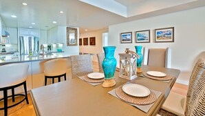 A dining area with a wooden table set for four, surrounded by wicker chairs. - Stunning Oceanfront Getaway at Windansea Beach (San Diego)