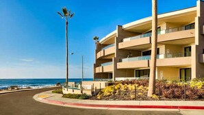 A beachfront hotel with multiple balconies, a palm tree, and a view of the ocean. - Stunning Oceanfront Getaway at Windansea Beach (San Diego)