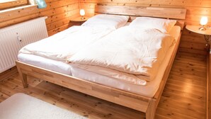 A wooden bed in a cabin-style room with two bedside tables and a window. - Doppelhaushälfte in Hasselfelde (Hasselfelde)