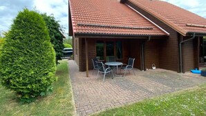 A wooden house with a tiled roof, a paved patio, and a small table with chairs. - Doppelhaushälfte in Hasselfelde (Hasselfelde)