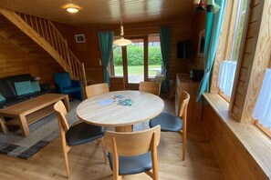 A cozy cabin interior with a wooden dining table, chairs, a sofa, and a staircase. - Doppelhaushälfte in Hasselfelde (Hasselfelde)