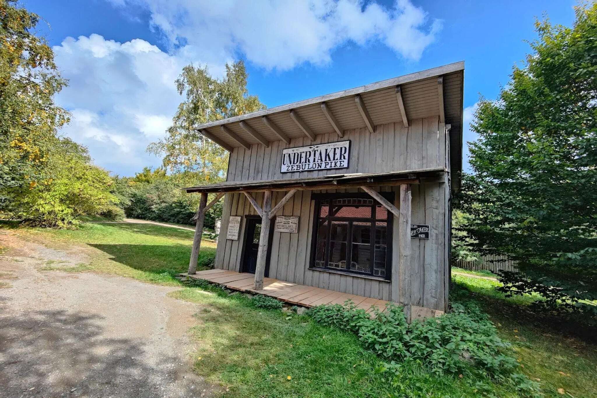 A wooden building with a sign reading "UNDERTAKER ZEBULON PINE."