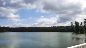 A lake with a forested shoreline and a white railing in the foreground. - Doppelhaushälfte in Hasselfelde (Hasselfelde)
