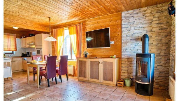 Un intérieur de chalet chaleureux comprenant un coin repas, une cuisine et un poêle à bois.