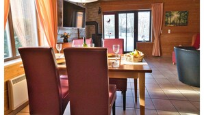 Un espace repas comprenant une table, des chaises, un téléviseur et une vue sur l’extérieur.