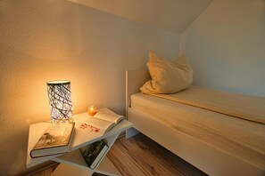 Una habitación pequeña y acogedora con una cama, una mesita de noche con lámpara y un libro.
