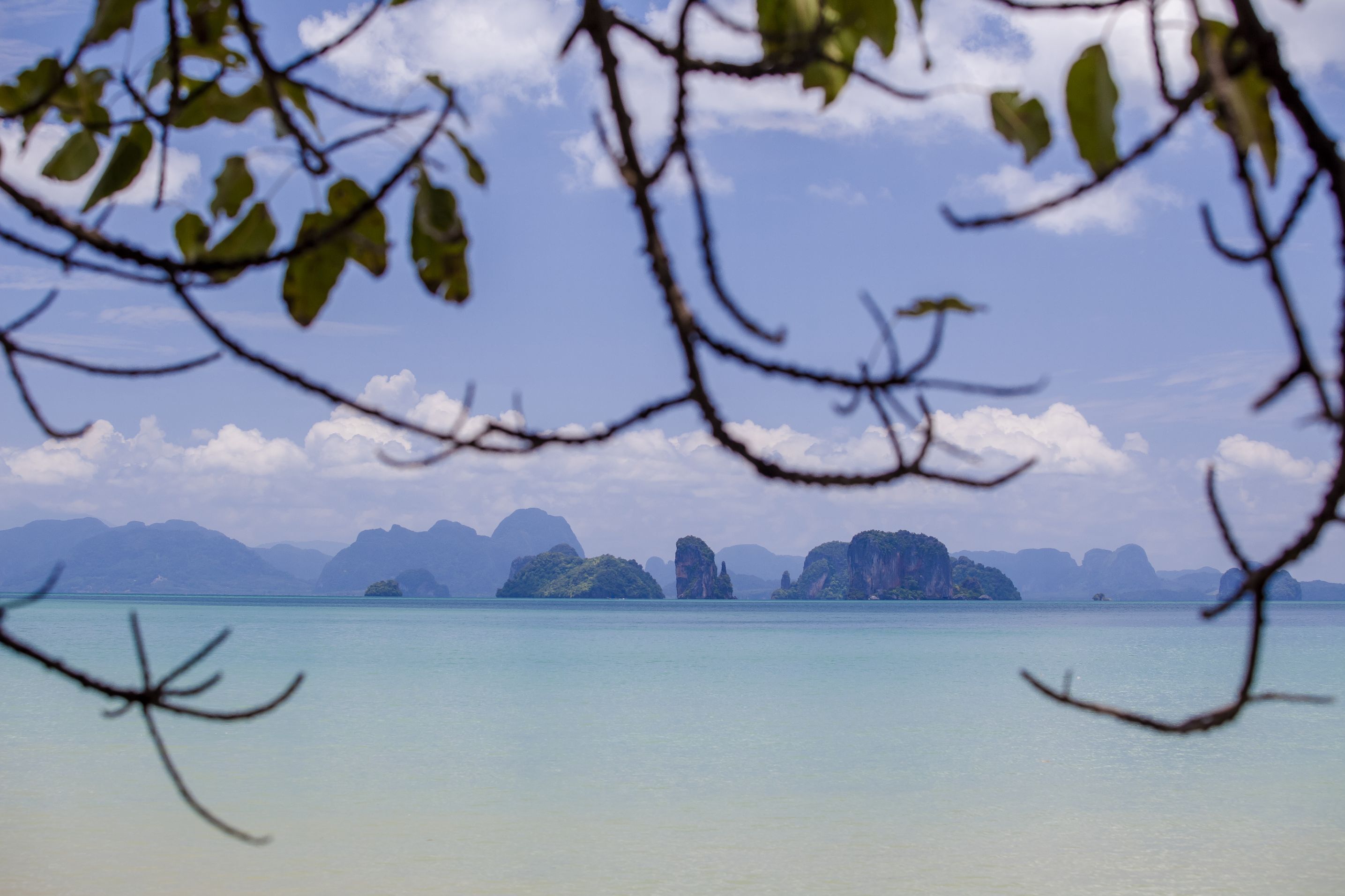A coastal view with clear water, distant islands, and a clear sky.