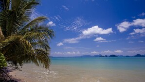 A beach with clear turquoise water, a palm tree, and distant islands under a blue sky with clouds. - Villa Lydia, Koh Yao Noi (Ko Yao)