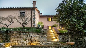 A stone staircase leading to a house with a tiled roof, surrounded by greenery and a stone wall. - Country House "IL CERRO" (Toscana)