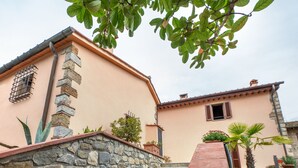 A two-story building with stone steps leading to a door, surrounded by greenery and a clear sky. - Country House "IL CERRO" (Toscana)