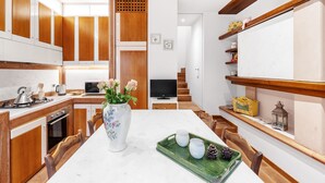 A modern kitchen with wooden cabinets, a marble countertop, and a dining area with a white table and chairs. - Country House "IL CERRO" (Toscana)