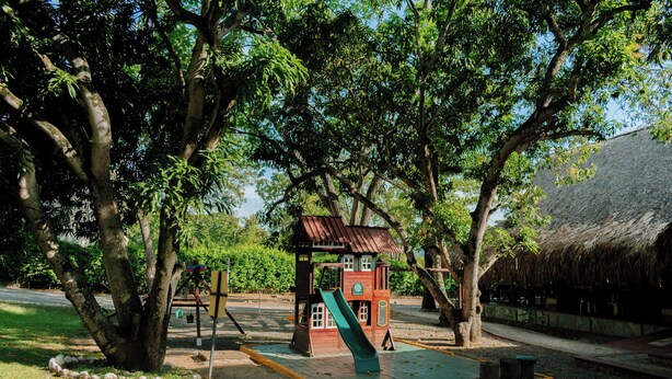 A playground with a slide, swings, and a small building with a thatched roof. - Hotel Porton del Sol  (Santa Fe de Antioquia)