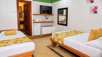 Habitación de hotel con dos camas, televisor, refrigerador pequeño y un espejo en la pared.