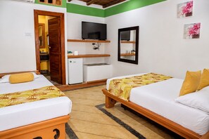 Habitación de hotel con dos camas, televisor, refrigerador pequeño y un espejo en la pared.