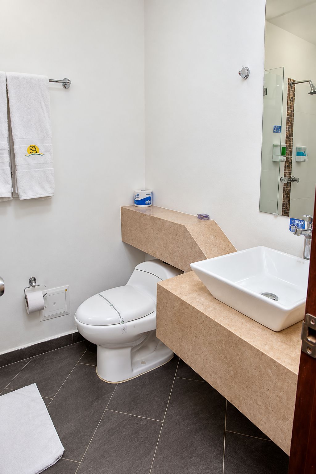 Un baño moderno con inodoro, lavamanos y espejo.