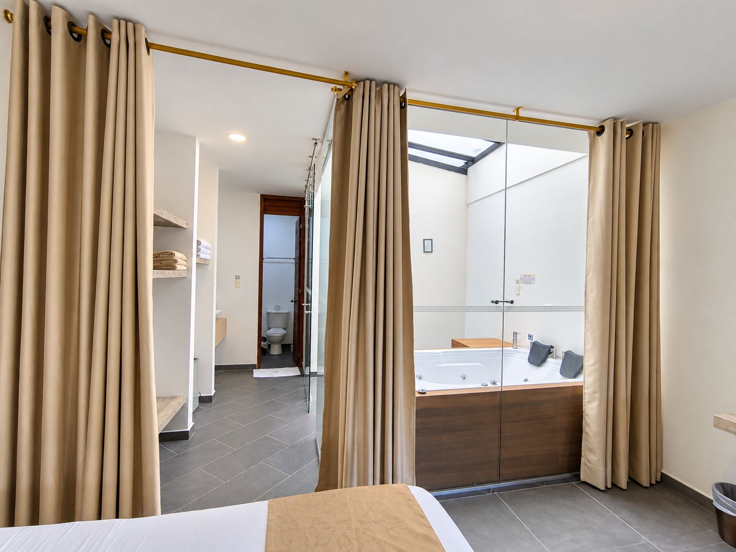 Une chambre d’hôtel avec un lit, une salle de bain avec une baignoire et un grand miroir.