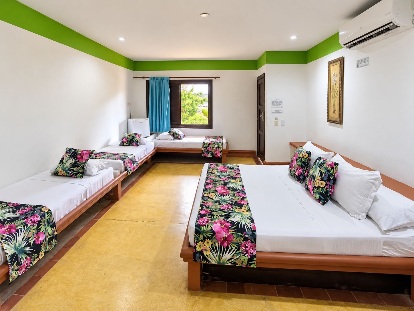 A hotel room with two single beds and one double bed, all with floral bedspreads.