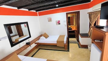 A compact hotel room with two beds, a large mirror, a television, and a small kitchenette.