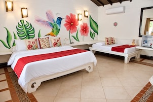Habitación de hotel con dos camas, un mural de colibrí y flores, y un minibar.