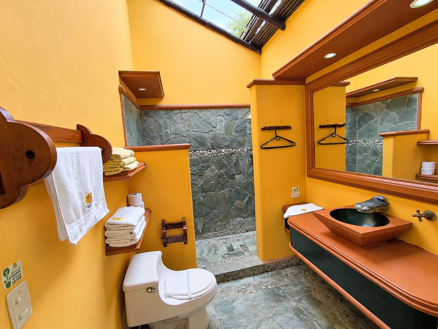 Une salle de bain comprenant des toilettes, un lavabo, un porte-serviettes et un mur en pierre.