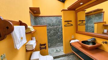 Une salle de bain comprenant des toilettes, un lavabo, un porte-serviettes et un mur en pierre.