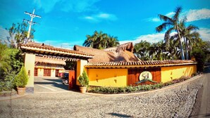 A building with a thatched roof, yellow walls, and a sign indicating it is a hotel. - Hotel Porton del Sol  (Santa Fe de Antioquia)