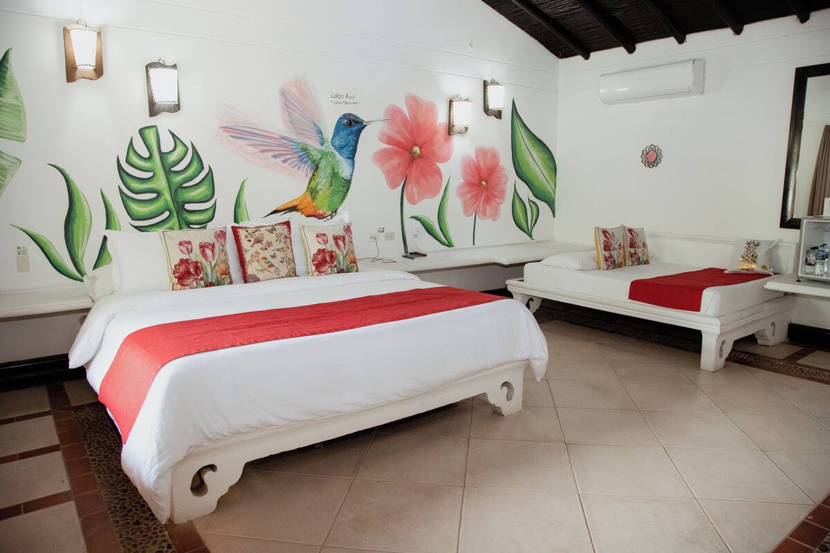 A hotel room with a large bed, a smaller bed, and a nightstand.
