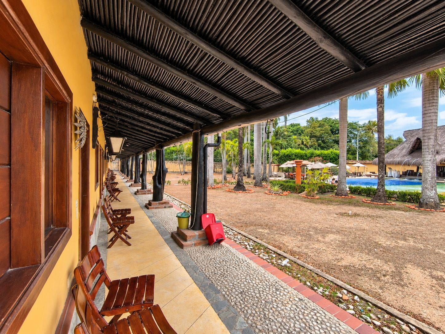 Un'area relax all'aperto con panchine in legno e una piscina sullo sfondo.