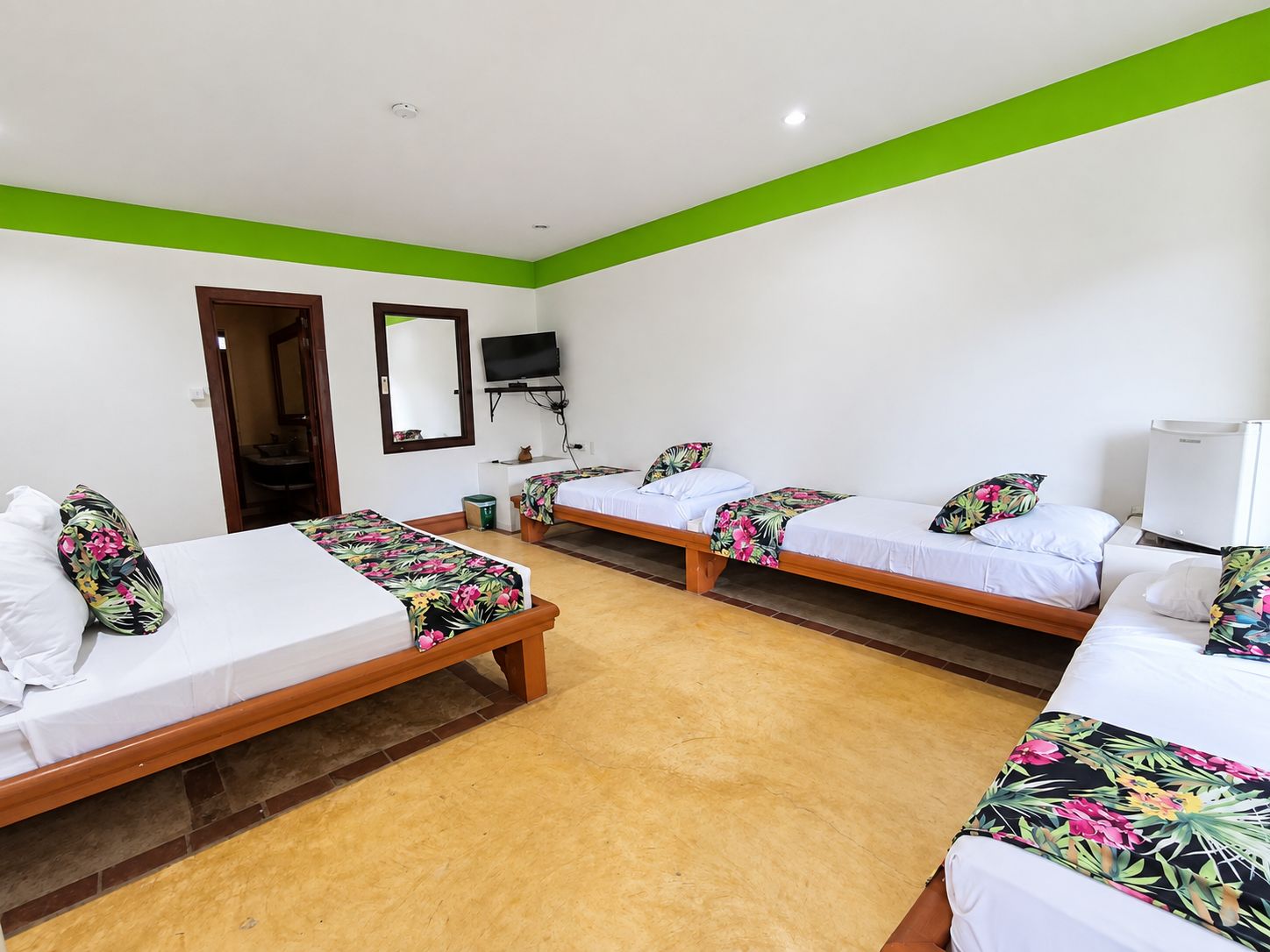Habitación de hotel con dos camas individuales, un televisor y un espejo.