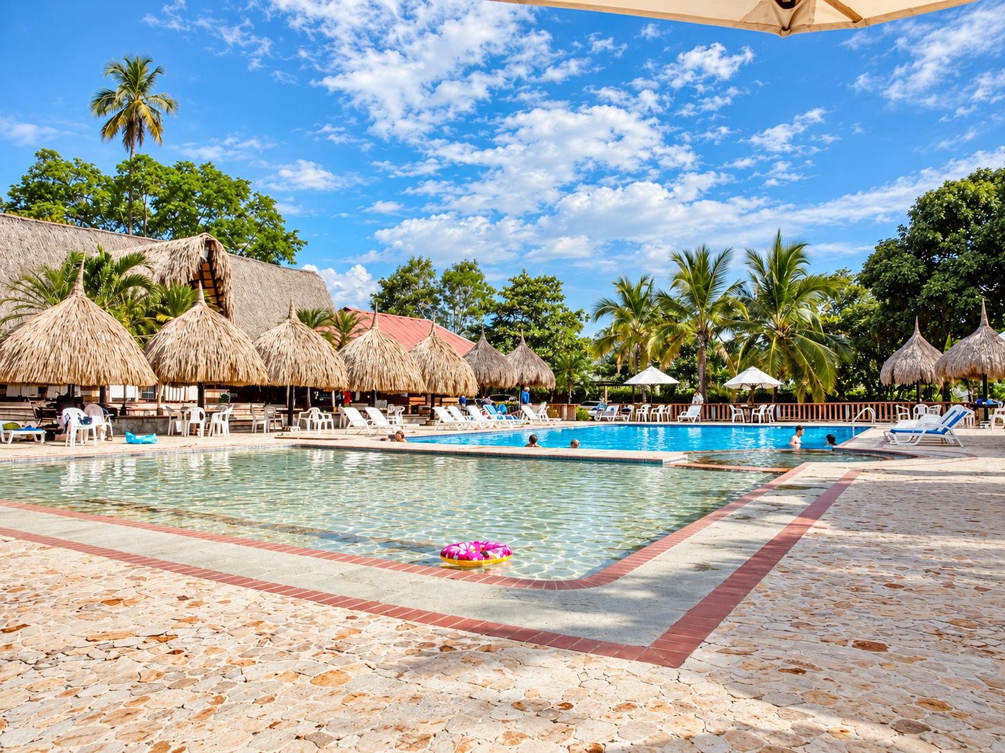 Un espace piscine avec des chaises longues et des parasols en chaume.