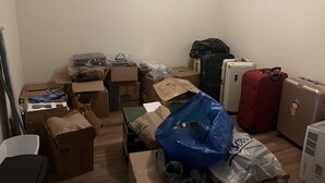 A room with various boxes, a suitcase, and a radiator.