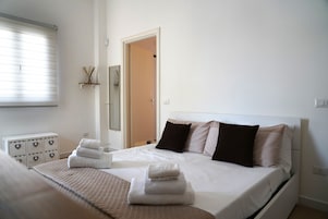 Un dormitorio ordenado con cama, cómoda y ventana con persianas.