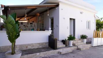 Stylish building with a clean design, featuring a covered porch and potted plants.