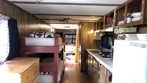 A compact cabin with bunk beds, a kitchenette, and wooden walls. - Antique1958Spartan CamperOceanLakes Cmpgrnd, I-33.Golf Cart for July,Aug rentals (Myrtle Beach)