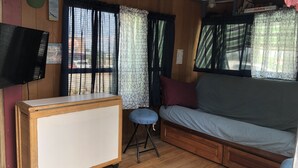 A compact room with a wooden bed, a small desk, and a television. - Antique1958Spartan CamperOceanLakes Cmpgrnd, I-33.Golf Cart for July,Aug rentals (Myrtle Beach)