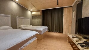 A hotel room with two single beds, a wooden floor, a television, and a curtain. - A BA LI BI Duck (Tainan)
